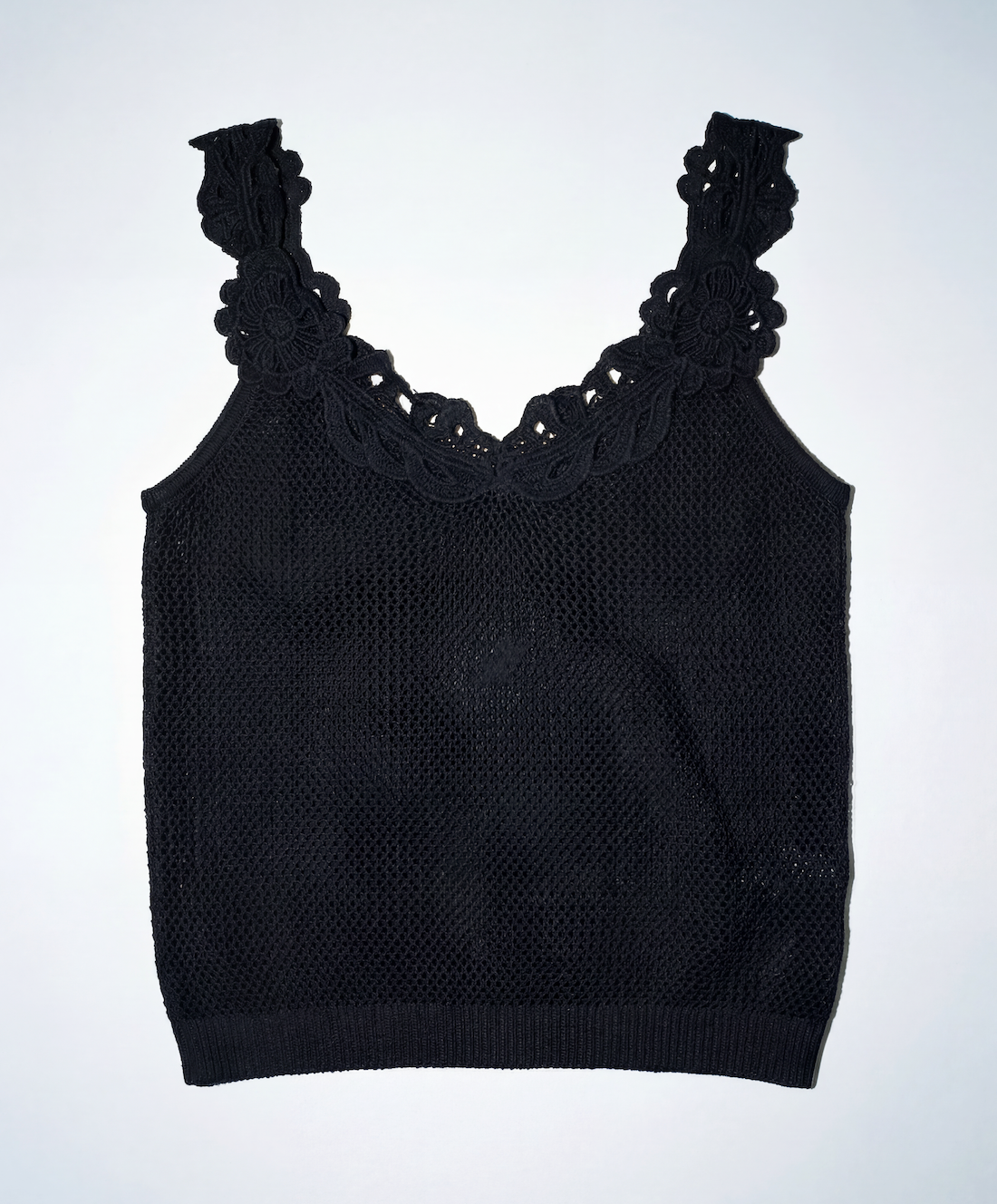 Black knit tank top with lace details on a white background